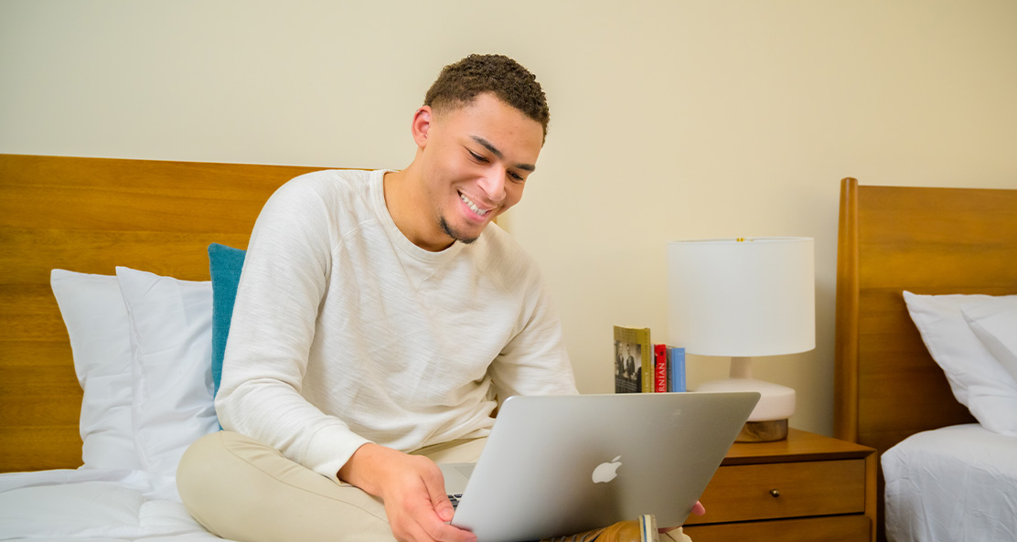 a guy patient sitting on his bed working on his laptop